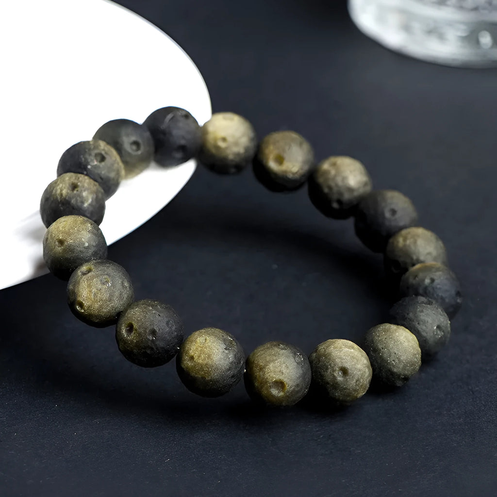 Natural obsidian crater ball bracelet in silver or gold finish, showing textured bead detail.