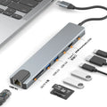 Silver USB-C 7-in-1 expansion dock with HDMI, USB ports, card slots, Ethernet, and a 15 cm cable.