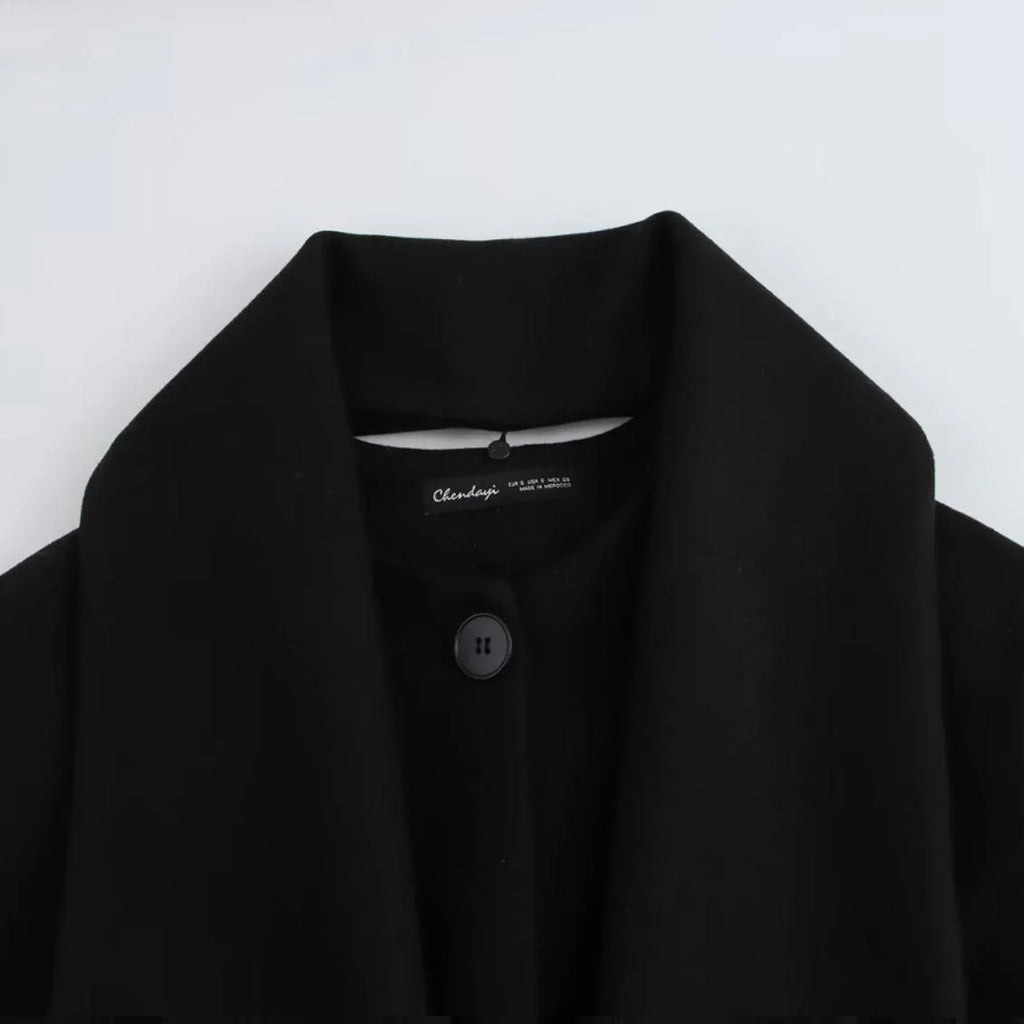 Women's long black coat with artificial fur collar, showing extended length and pocket detail.
