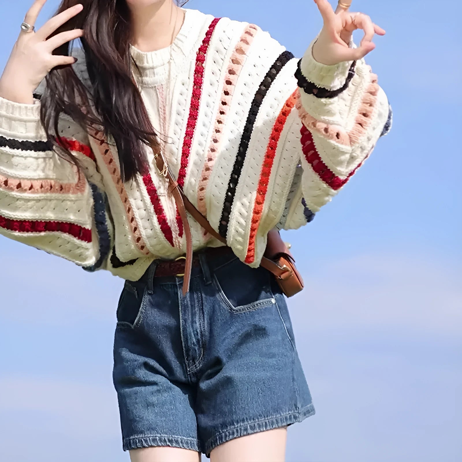 Retro rainbow striped hollow pullover sweater with batwing sleeves on a hanger.