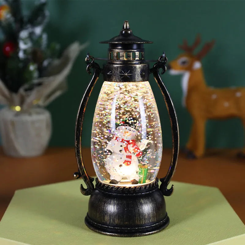 Plastic crystal ball LED oil lamp Christmas decoration showing internal snowman scene on a desktop.