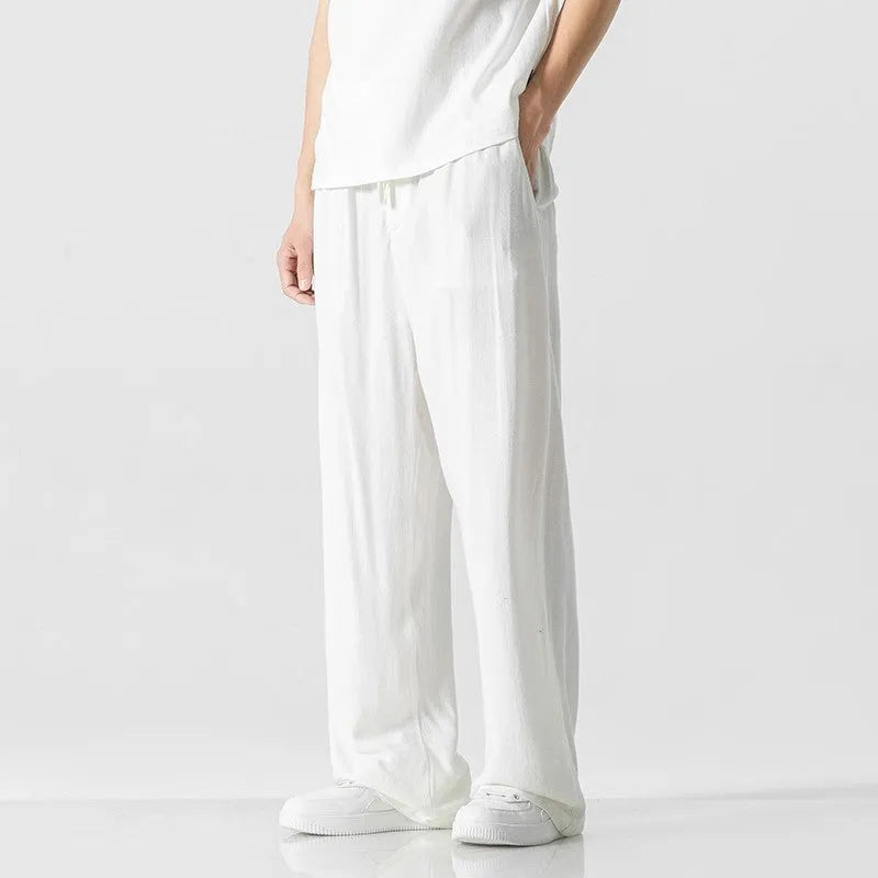 Man wearing beige cropped straight-leg bamboo fibre trousers with a drawstring waist on a summer day.