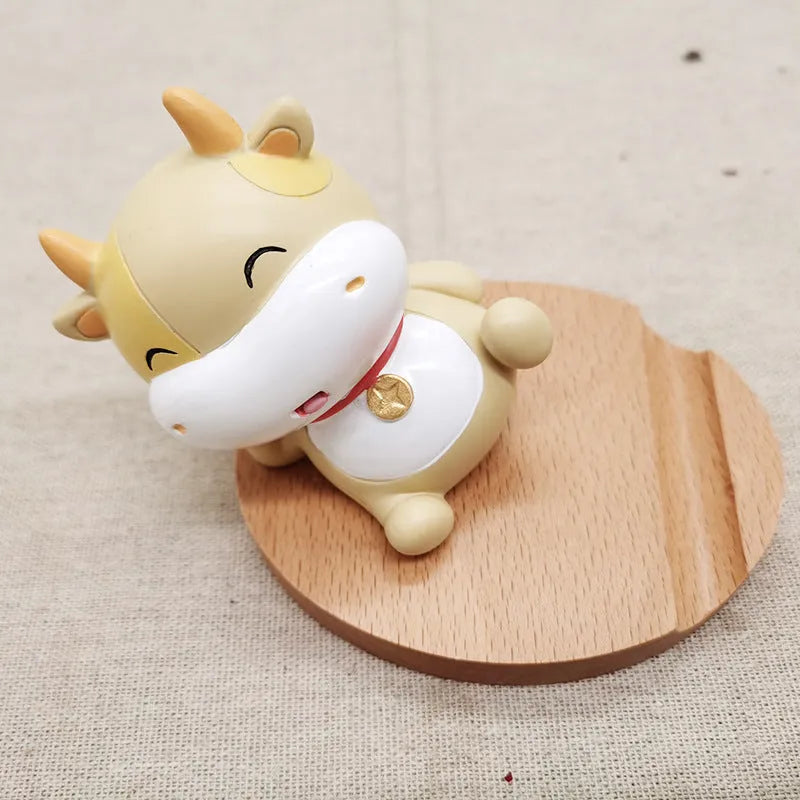Solid beech wood phone stand with a decorative resin puppy figurine, holding a mobile phone at an angle with a charging cable threaded through the back.