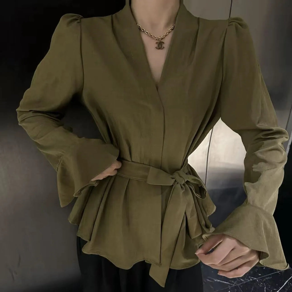 Woman wearing a black tied shirt with a French-style collar and long bell sleeves.