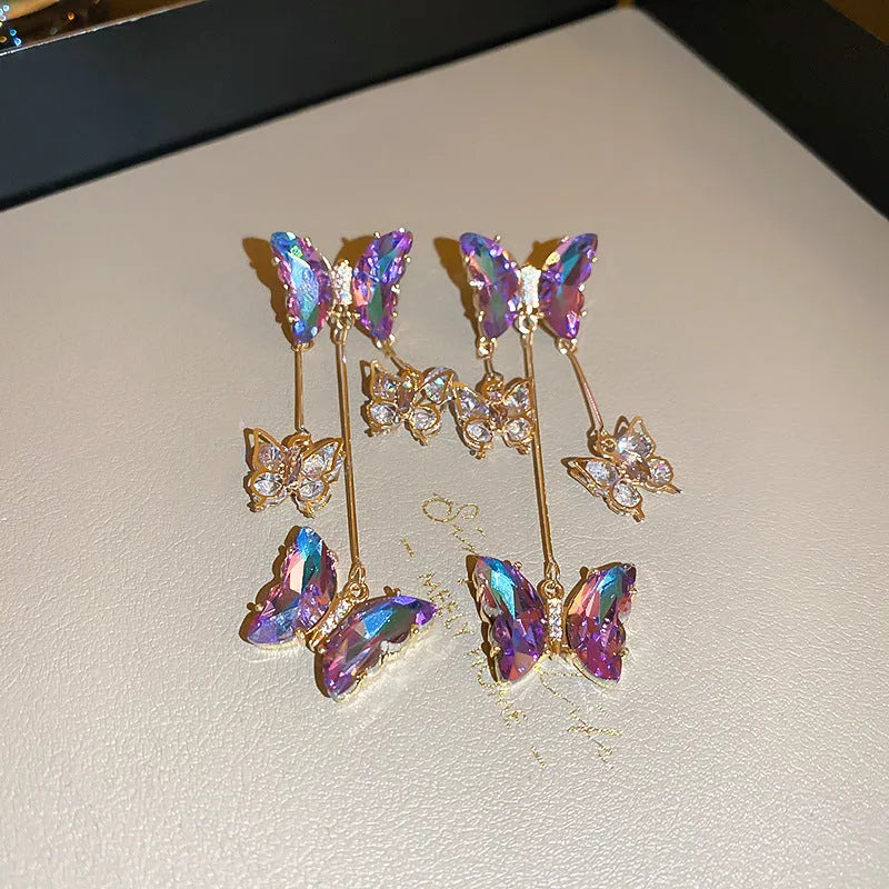 Silver Needle Blue Purple butterfly and crystal flower tassel drop earrings on a white background.