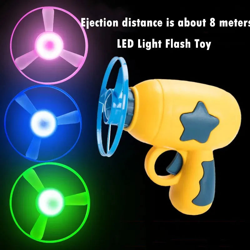 Blue plastic flying saucer launcher toy with LED-lit discs on a yellow target board.