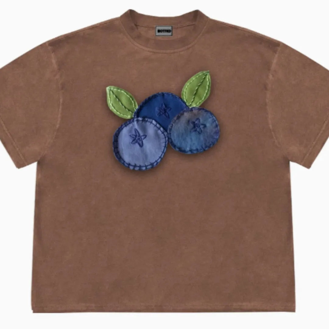 Loose fit blueberry fruit patchwork print short sleeve T-shirt on a hanger.