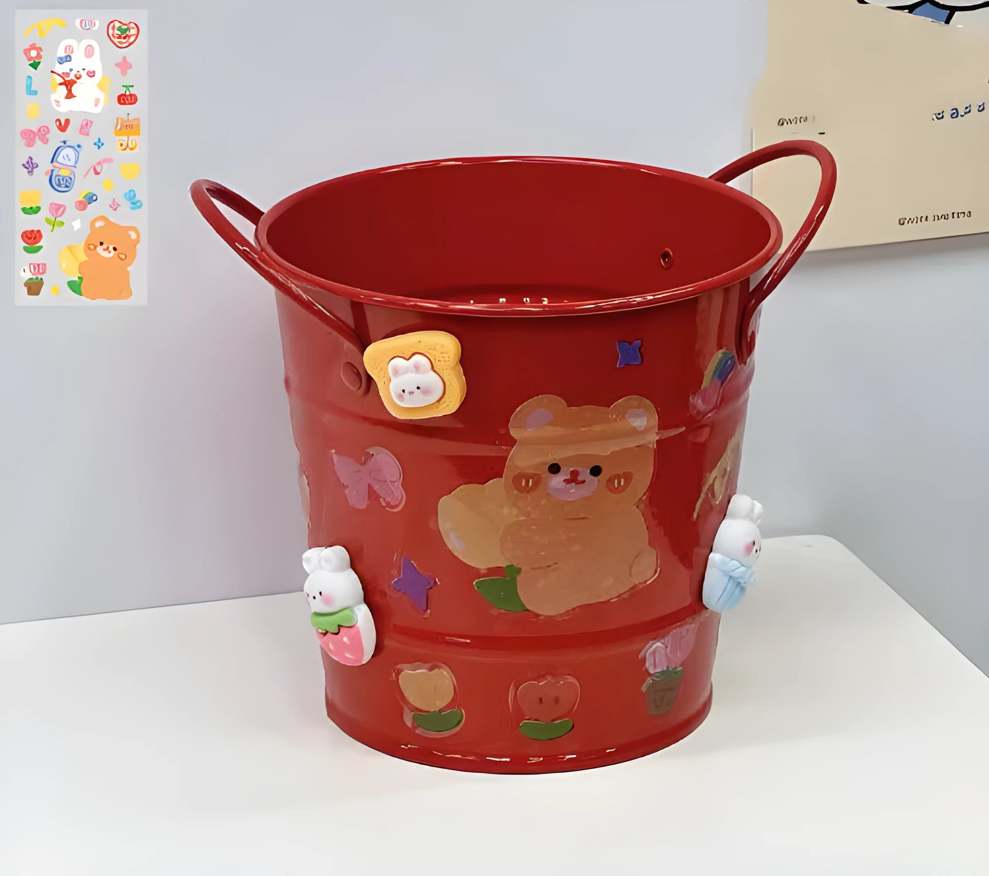 Round metal pen holder in a choice of colours, some with decorative sticker patches, on a wooden desk.