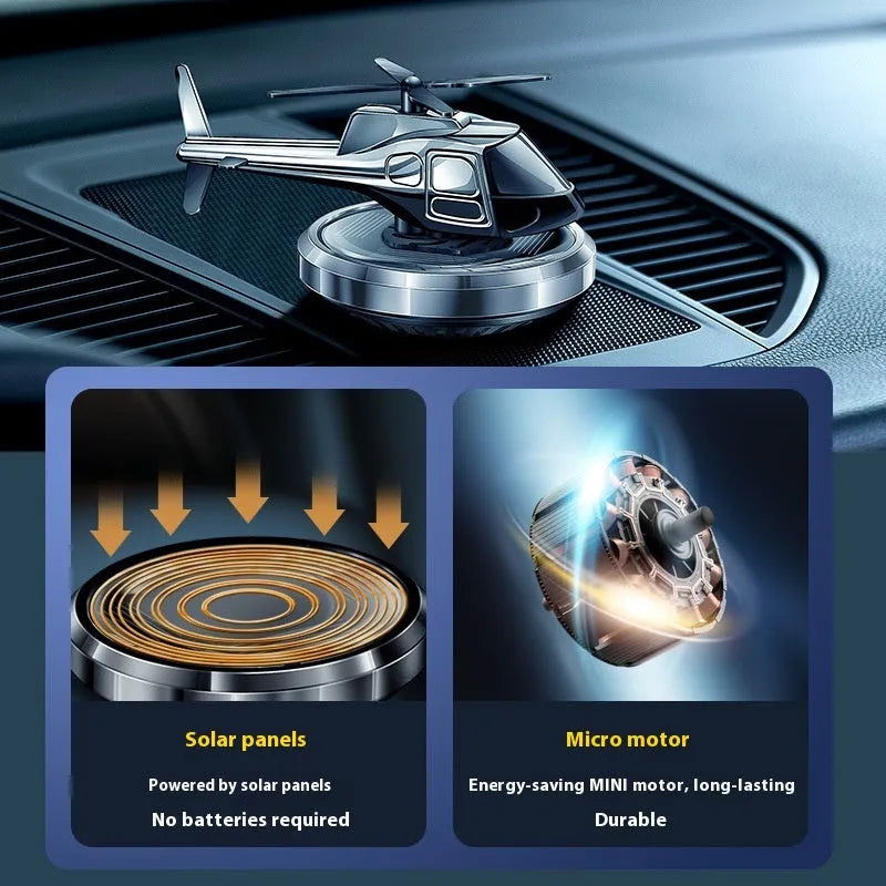 Silver metal solar-powered helicopter car air freshener with rotating blades on a dashboard