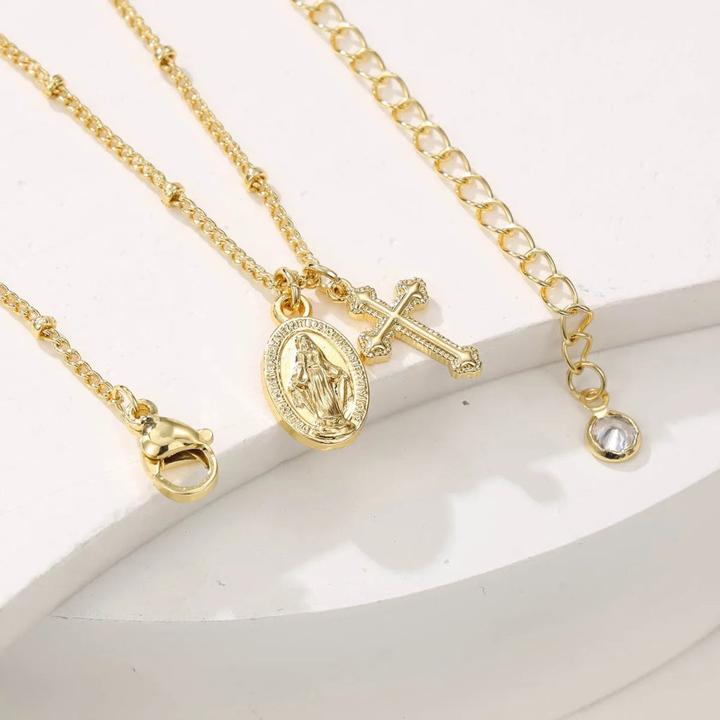 Geometric gold cross Virgin Mary pendant necklace with a simple design on a chain.