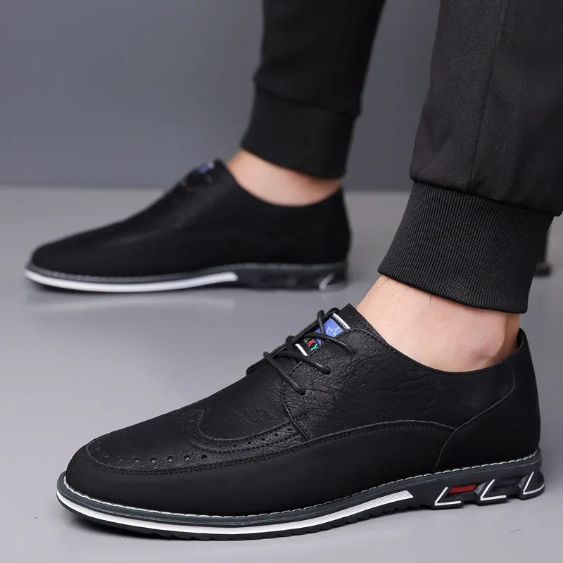 Men's black leather slip-on shoes with a rubber sole and leather toe cap on a grey background.