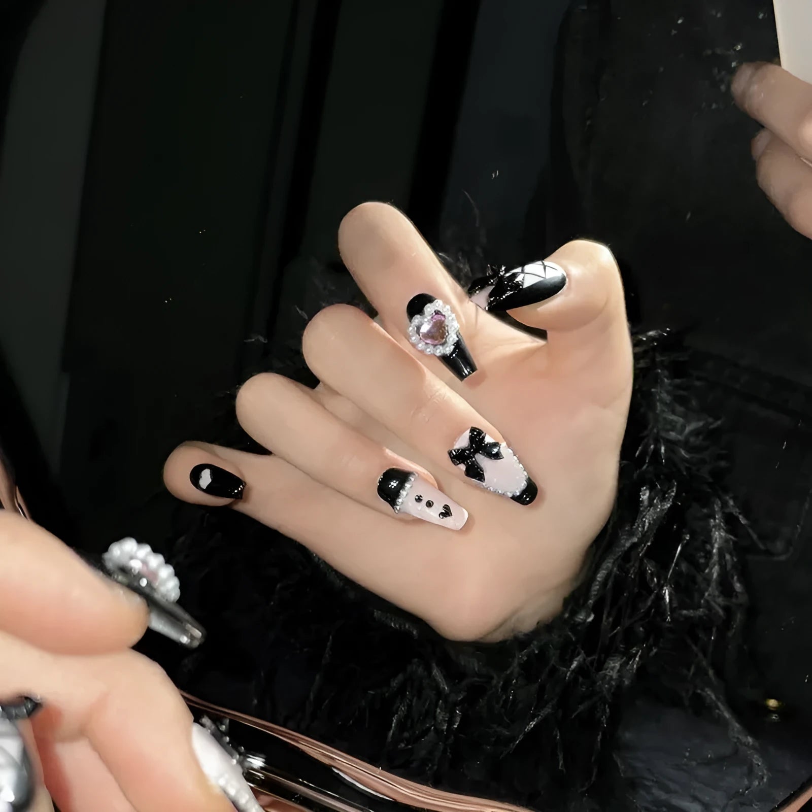 Hand-painted black and pink heart design on detachable plastic manicure nails in cat's eye style.