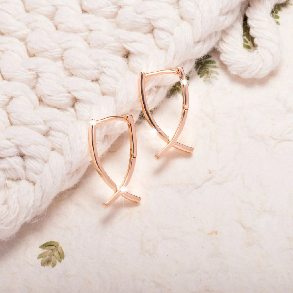 Rose gold cross shaped earrings with a polished finish on a solid copper base.