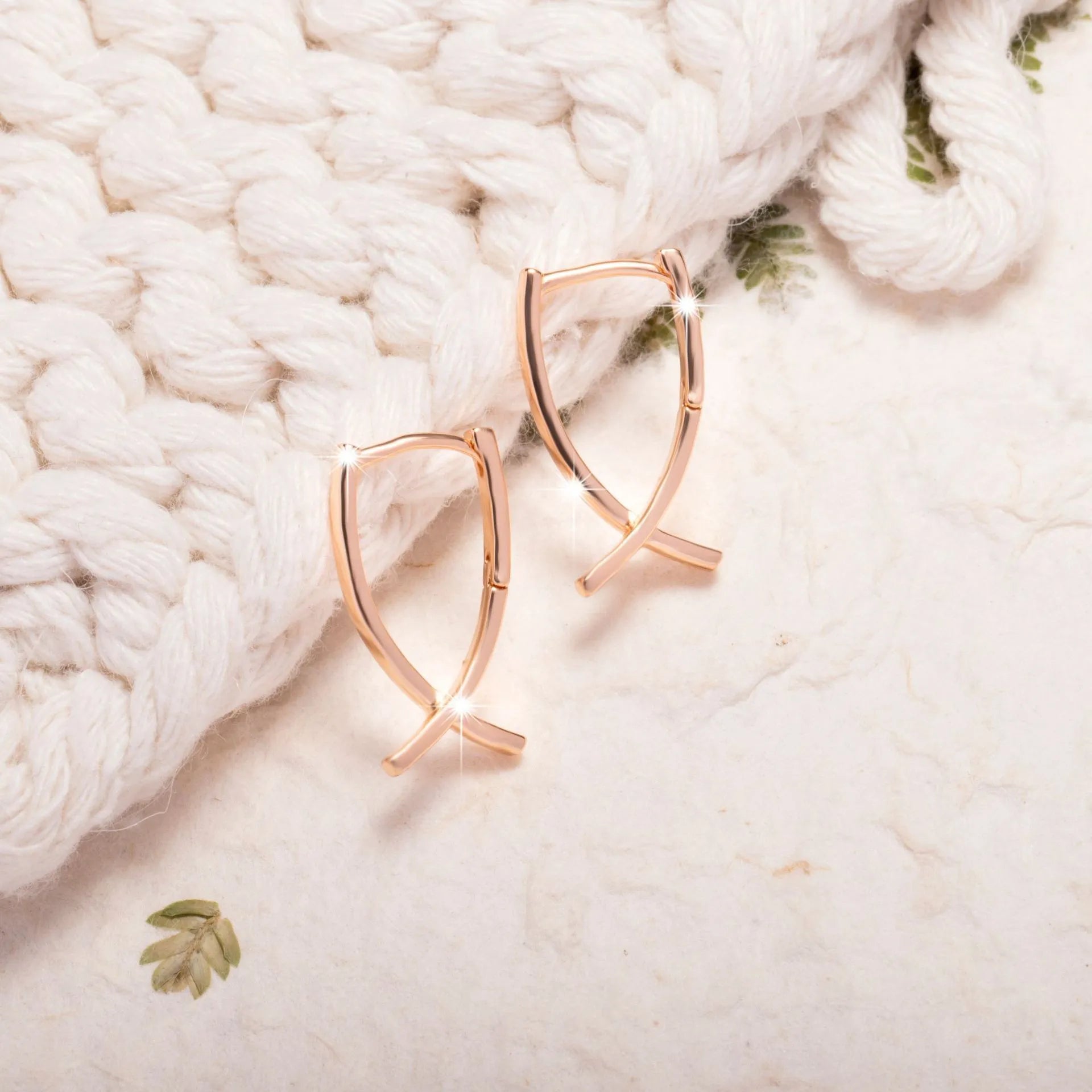 Small rose gold plated copper cross dangle earrings on a white background.