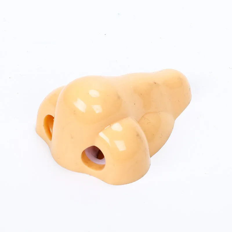 Flesh-coloured plastic pencil sharpener with large nostril and geometric shape on a white background.