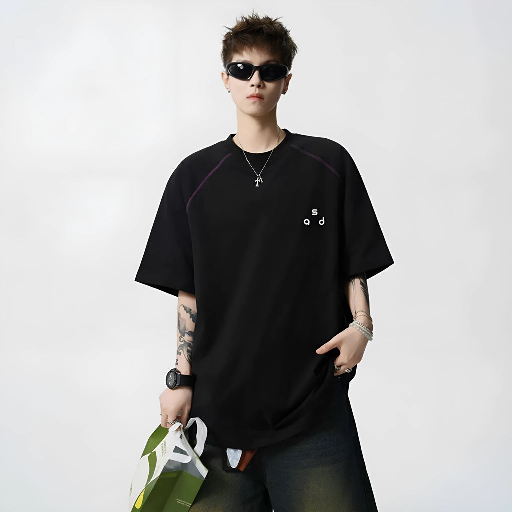 Man wearing a loose-fitting black cotton T-shirt with a white letter print on the chest.
