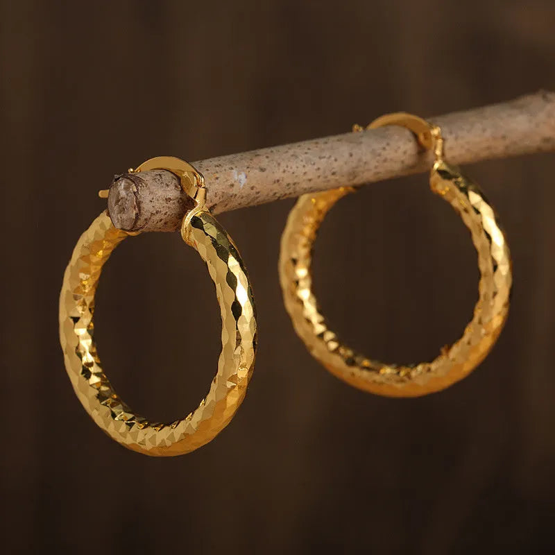 Pair of gold-coloured retro classic alloy earrings for women on a neutral background
