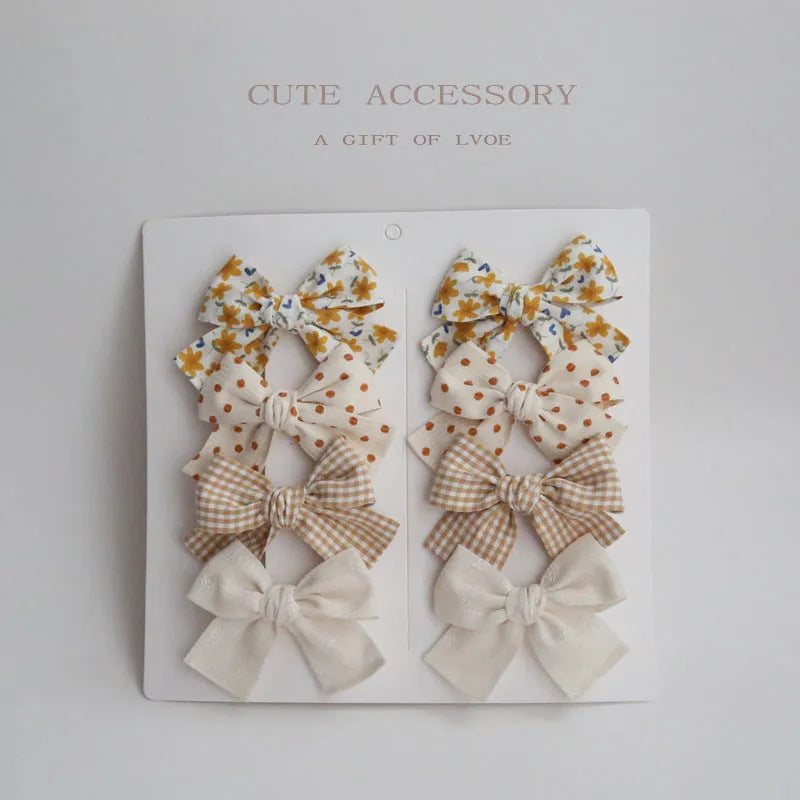 Set of children's cloth hairclips with a dovetail bow design in various colours including beige and blue flowers.