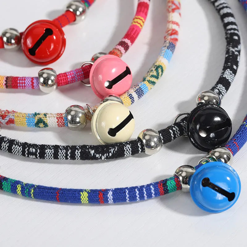 Coloured ethnic-pattern adjustable dog or cat collar with a small metal bell attached, shown in pink.