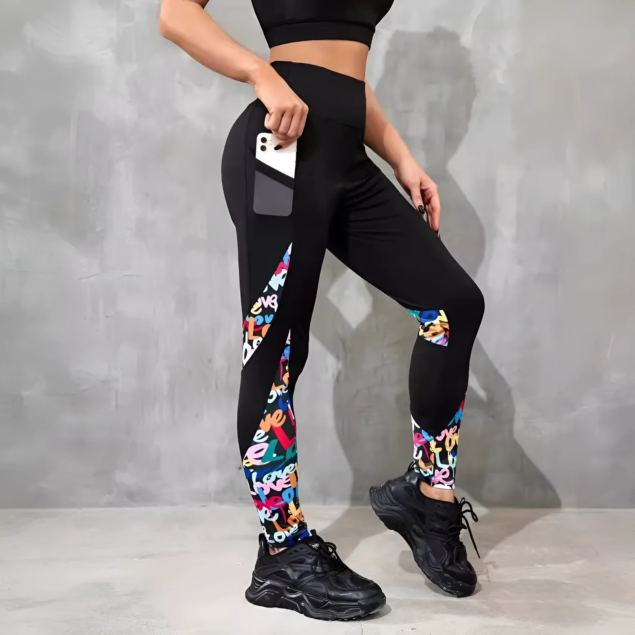 Black women's high-waisted yoga leggings with contrast patchwork design and side pocket.