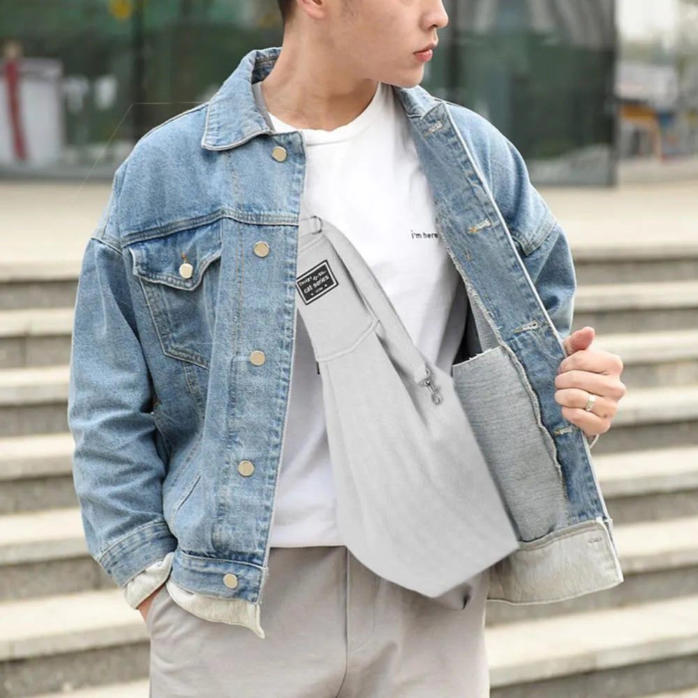 Light grey polyester pet sling carrier with cell phone pocket, worn around waist, holding a small dog