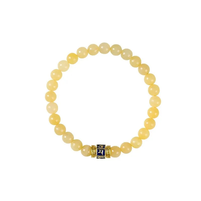 Close-up of a women's hand-woven bracelet with topaz-coloured barrel beads, square jade beads, and a fu charm.