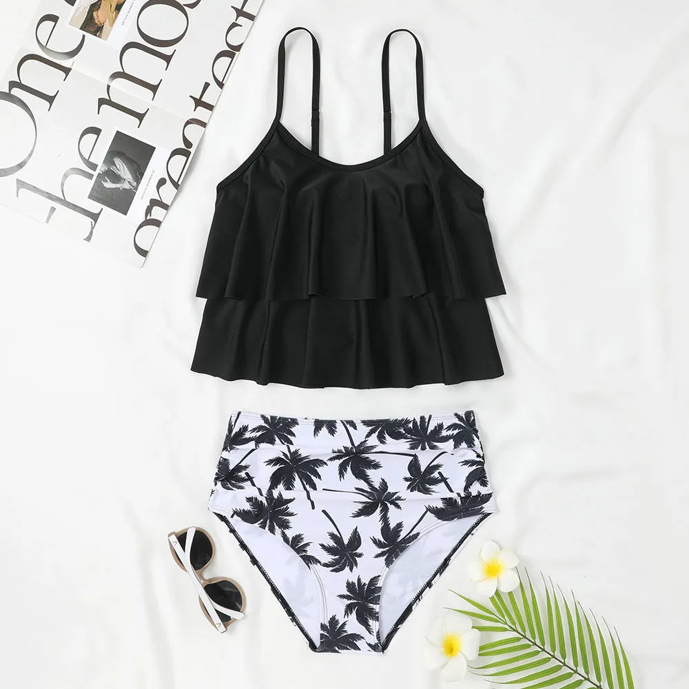 Black high waist swimsuit briefs and sleeveless top with coconut tree print, laid flat.