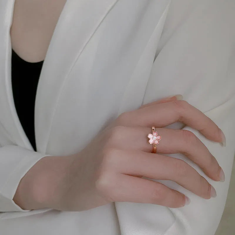 Cherry blossom rotatable ring with rose gold finish, adjustable opening, and silver base shown on a finger