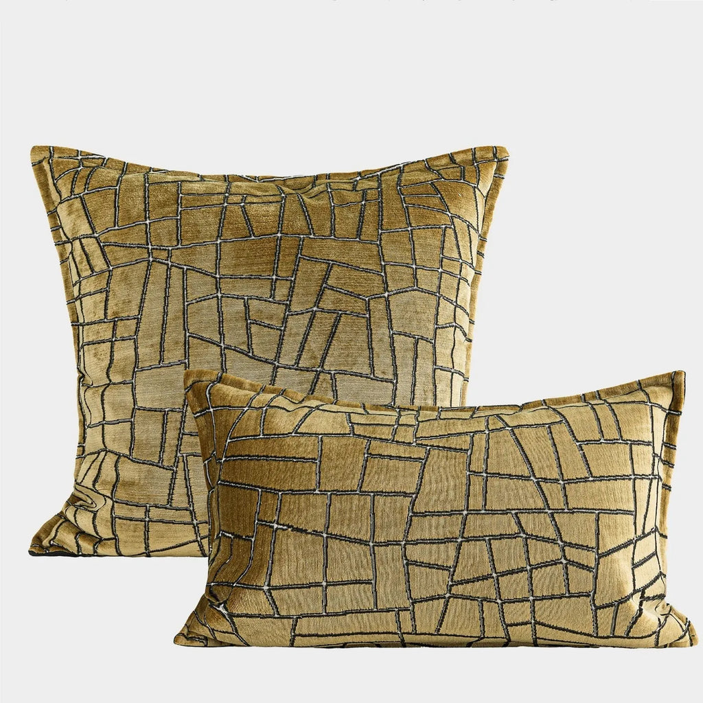 Geometric abstract patterned cushion cover in gold colour on a grey sofa, showing three size options.