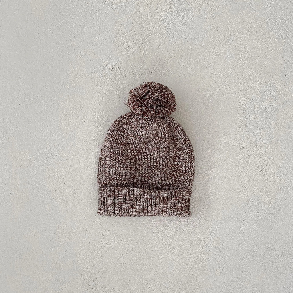 Dark brown knitted three-piece set for infant girl with fur ball hat, blouse, and shorts.