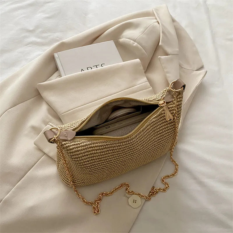 Khaki woven straw crossbody handbag with square shape and crossbody strap.