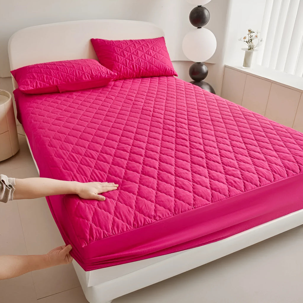Diamond quilted black waterproof mattress protector fitted sheet and pillowcases set on a bed