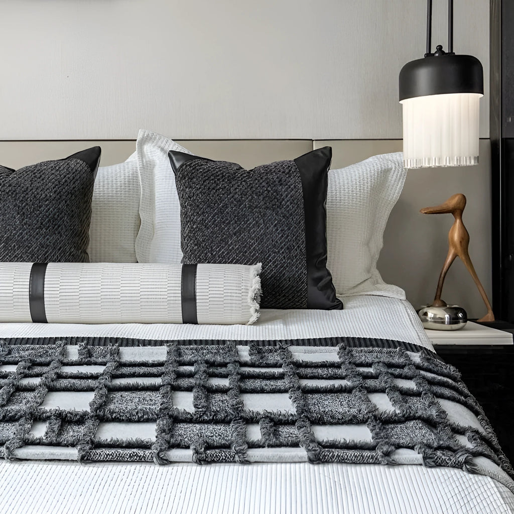 Modern grey and white plaid bed runner blanket set with round leather pillow on a bed.