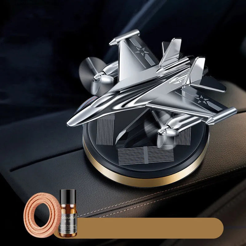 Solar powered rotating silver fighter jet car air freshener ornament on a dashboard.