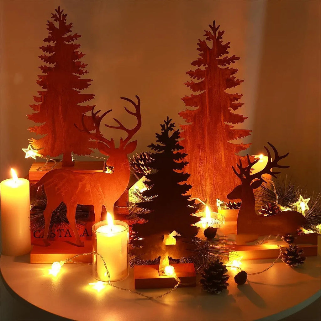Set of three rustic iron metal Christmas tree and elk silhouette ornaments on a wooden surface.