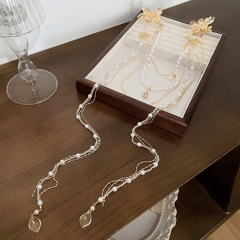 Women's gold pearl diamond flower long tassel hairpin on white background