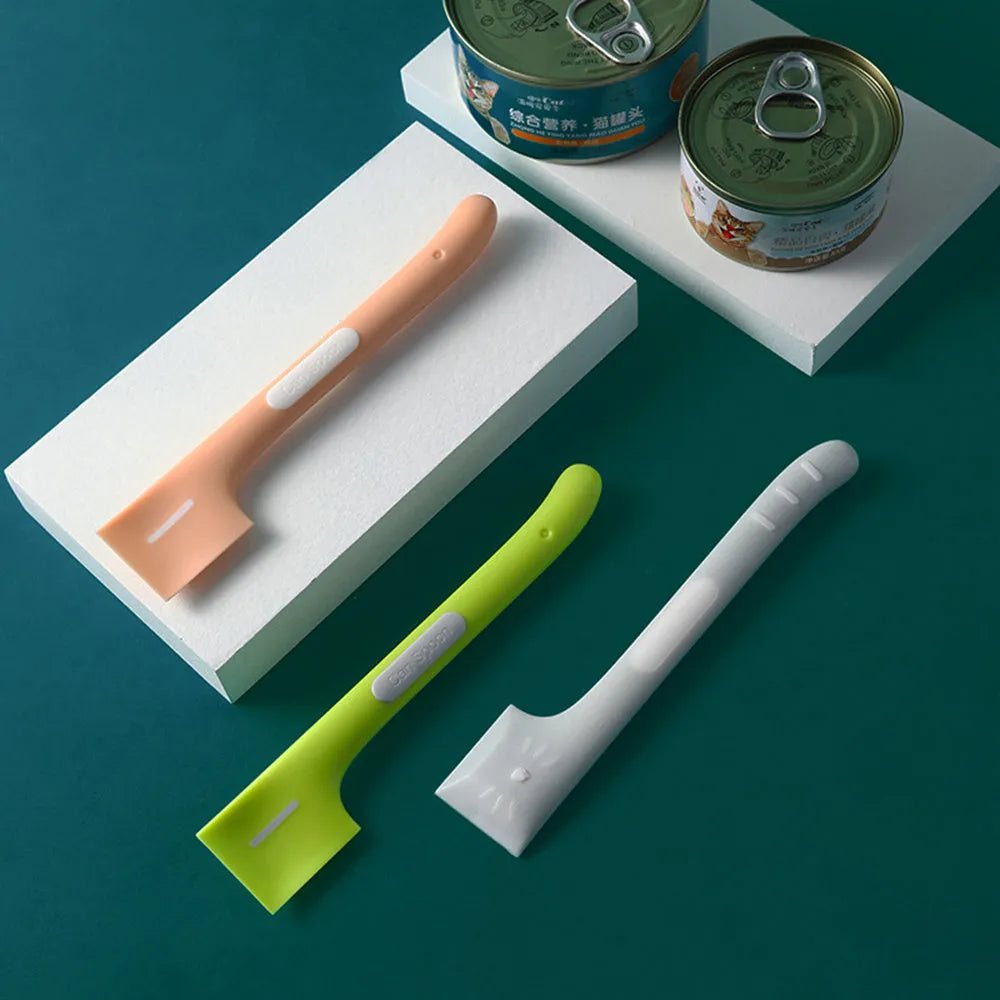 Green long-handled pet food spoon with angled head for scooping canned cat or dog food.