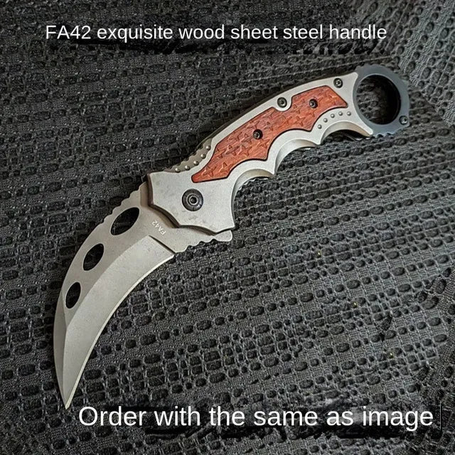 Folding claw knife with grey titanium blade and sour branch wood handle on a surface