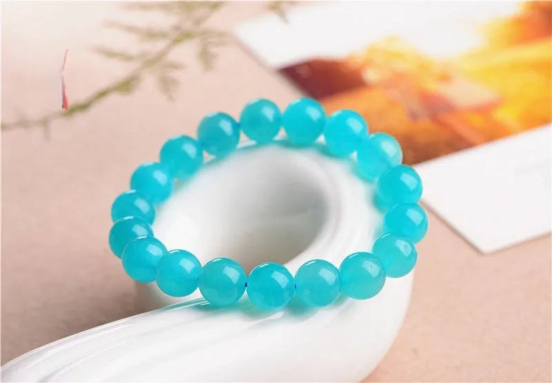 Selection of natural green Amazonite scattered beads in different sizes on a white background.