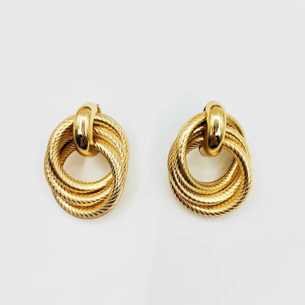 Gold geometric ring embossed twisted stud earrings on white background