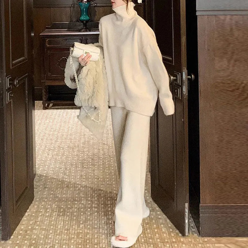 Women's beige acrylic knit long-sleeve sweater and matching wide-leg trousers set on a hanger.