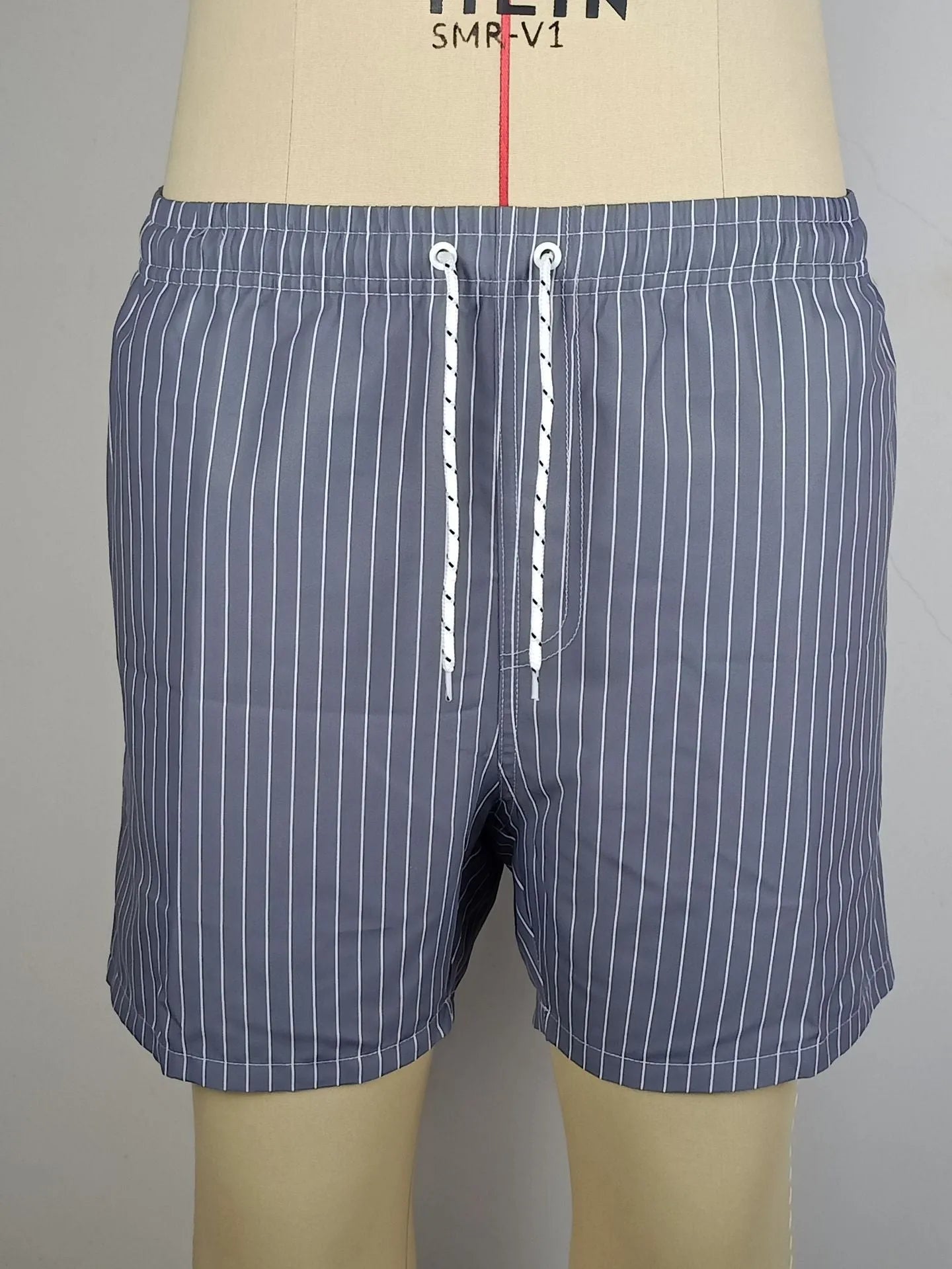 Men's navy blue polyester beach shorts with striped triangle lining and straight leg opening.