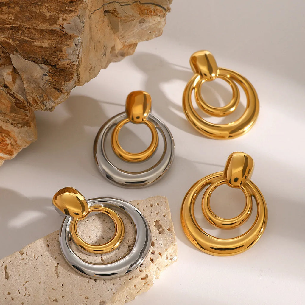 A pair of round, geometric double-layer hollow stud earrings with an 18K gold plated finish.