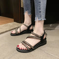 Women's silver flat sandals with rhinestone embellishment and an elastic strap on a rubber sole.