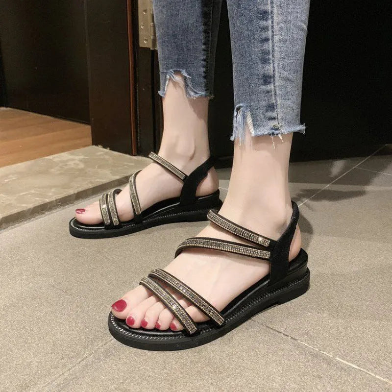 Women's silver flat sandals with rhinestone embellishment and an elastic strap on a rubber sole.
