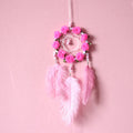 Close-up of a modern pink ostrich feather dreamcatcher wind chime wall ornament.