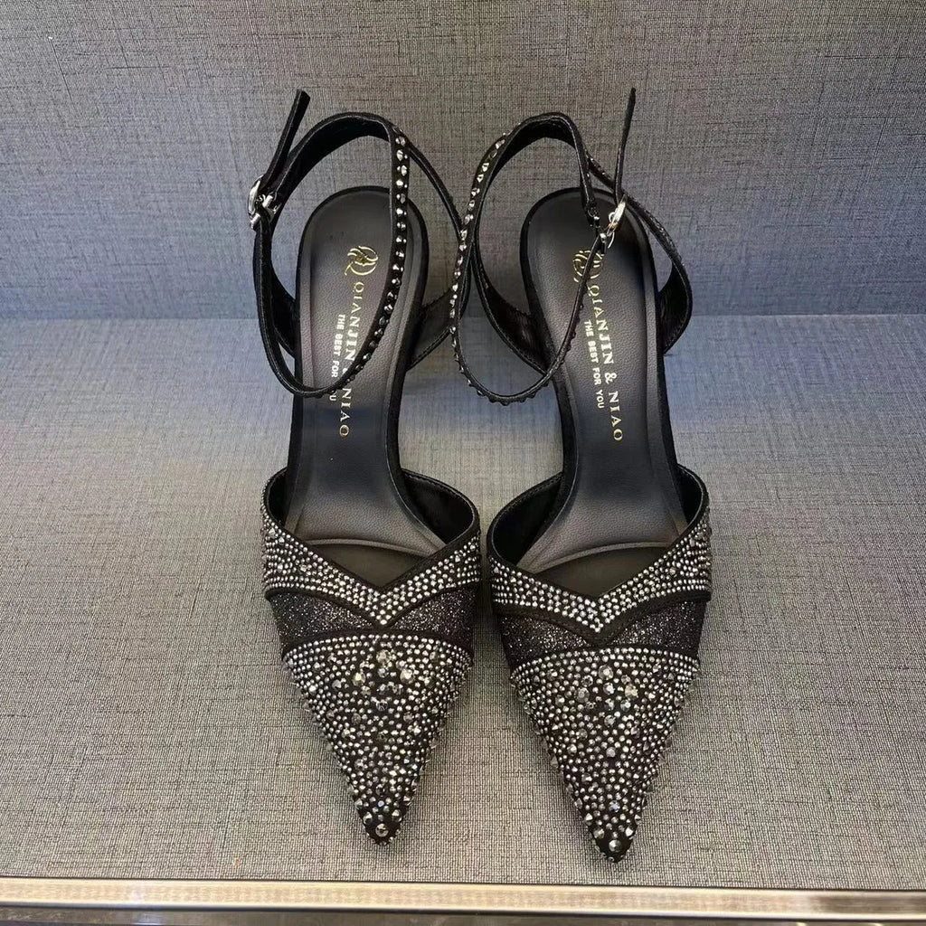 Women's black hollow high heel shoe with red sole and pointed toe, shown next to a silver pair.