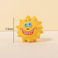 Set of four colourful latex squeaky dog balls with cute faces on a textured surface.
