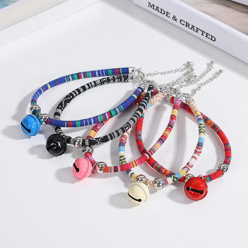 Coloured ethnic-pattern adjustable dog or cat collar with a small metal bell attached, shown in pink.