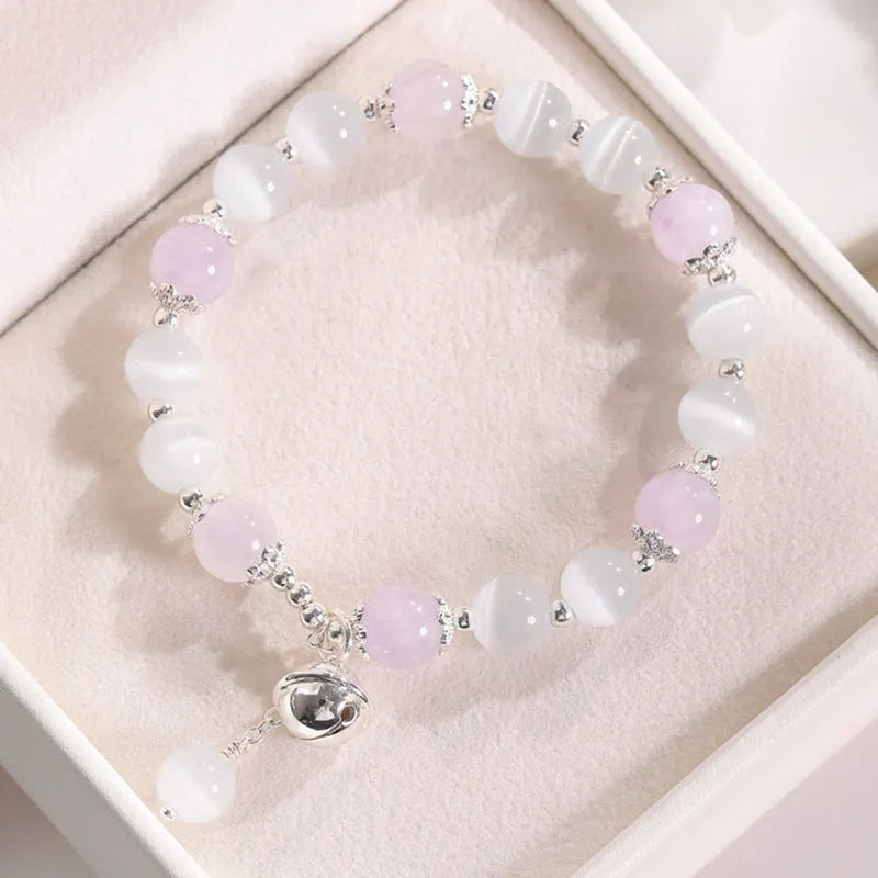 Close-up of a women's opal cat's eye stone beaded bracelet with diamond-shaped beads on a wrist.